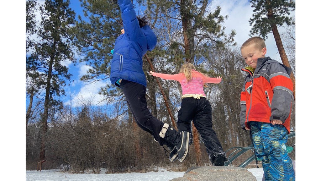 Kids catapult into a snowy field from a rock to play