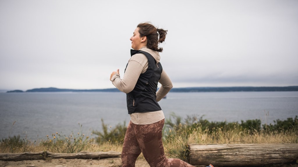 A woman jogs solo by a body of water