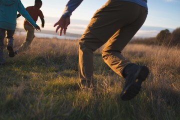 A dad chases two kids on a hike