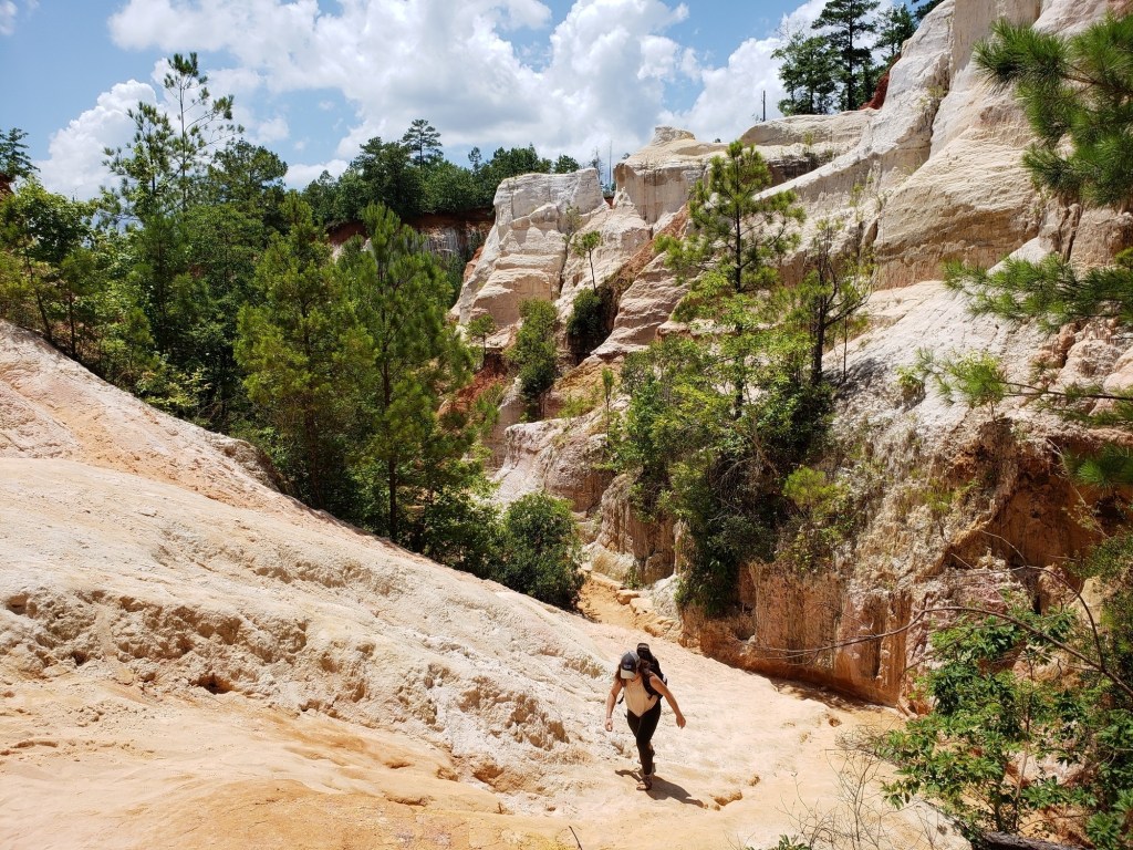 A hiker climbs a path through a canyon.