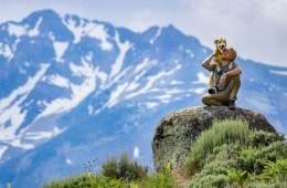Ben Moon with his dog, Nori, sitting on a rock with a mountain range behind them.