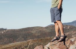 A man is standing on a rock in sandals.