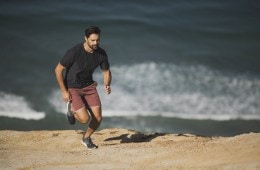 Joe Kudla running on the beach with the ocean in the background.