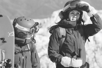 Edita Hadravska standing with ski poles in one hand with her hand shading her eyes.