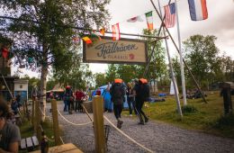Two hikers have their back to the camera as they walk underneath a Fjallraven Classic sign.