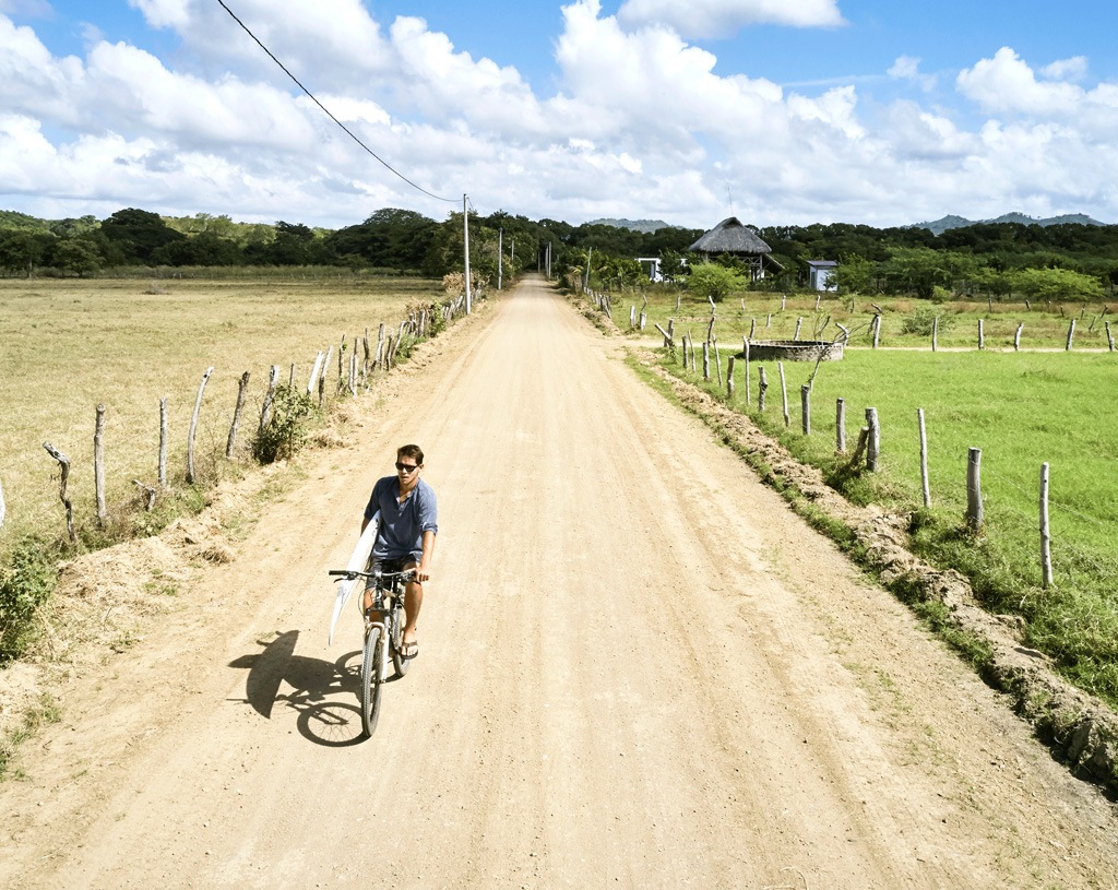Ernesto Martinez Hellmund cycles with his surfboard. 