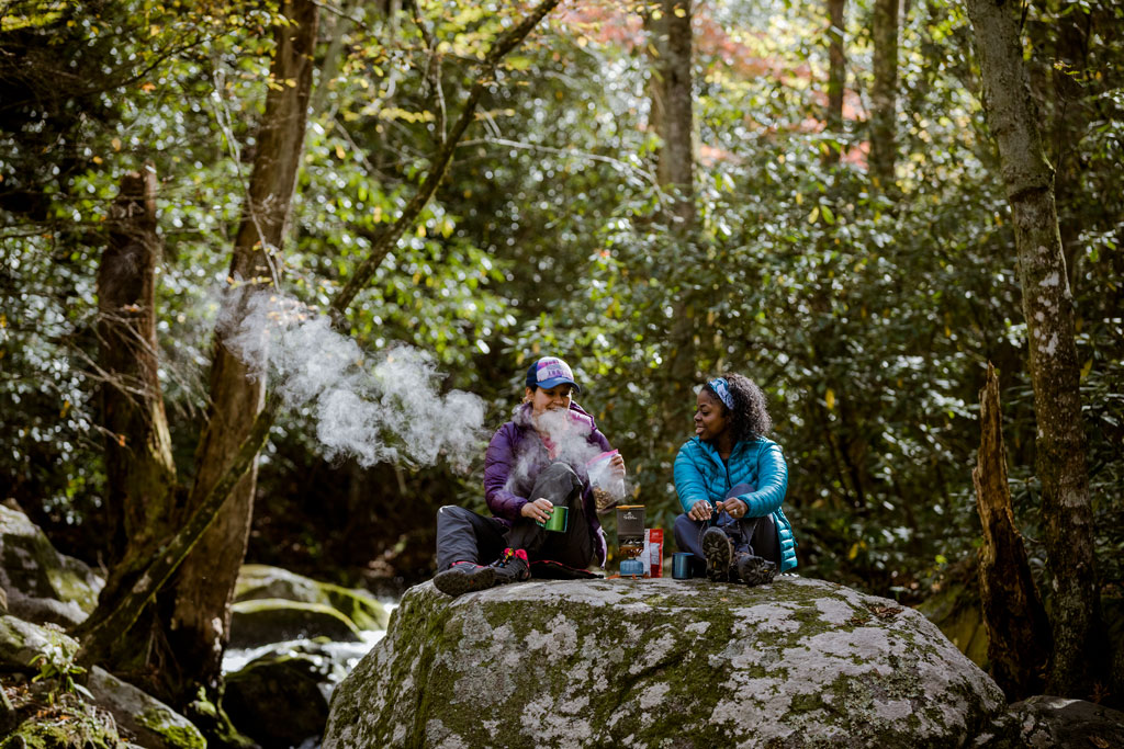 Two backcountry campers making food on a rock