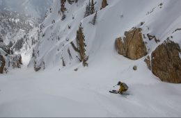 Noah Howell is skiing down a slope in the Wasatch Mountains in Utah, the photo is shot from above and behind