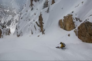 Noah Howell is skiing down a slope in the Wasatch Mountains in Utah, the photo is shot from above and behind
