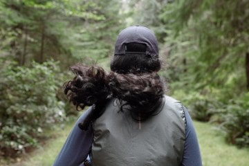 A woman jogs through a dense green forest