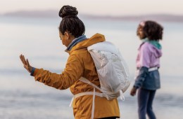Two women dancing on the beach; one of them wears the undyed Flash 22 pack from REI Co-op