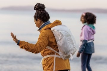 Two women dancing on the beach; one of them wears the undyed Flash 22 pack from REI Co-op