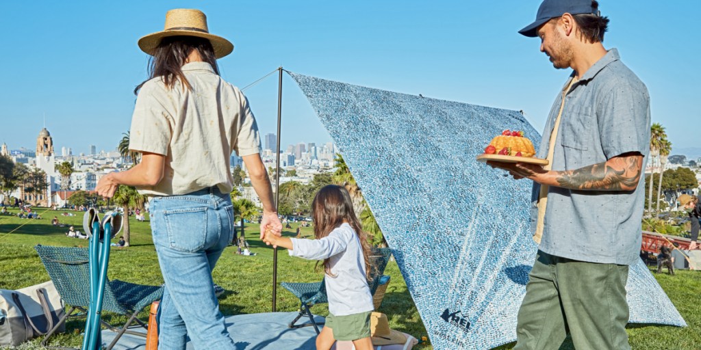 A family makes their way into the park with dinner party fixings in tow