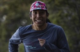 Christian Gering is smiling at the camera wearing a colorful hat as he runs towards the camera.