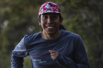 Christian Gering is smiling at the camera wearing a colorful hat as he runs towards the camera.