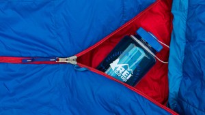 Blue water bottle nestled in a blue and red sleeping bag