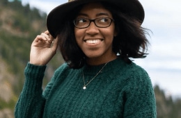 Tori smiling with her hand on the brim of her hat