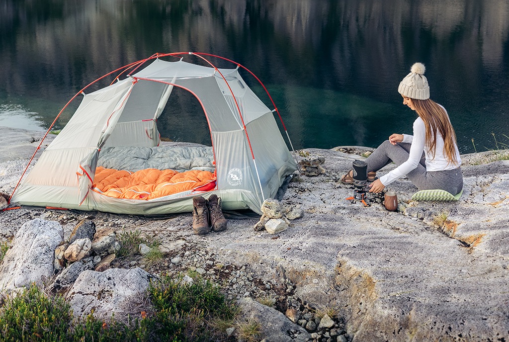Woman at campsite sits on pad