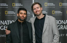Max Lowe smiles at the camera with his arms around another man. The backdrop says National Geographic Documentary Films.
