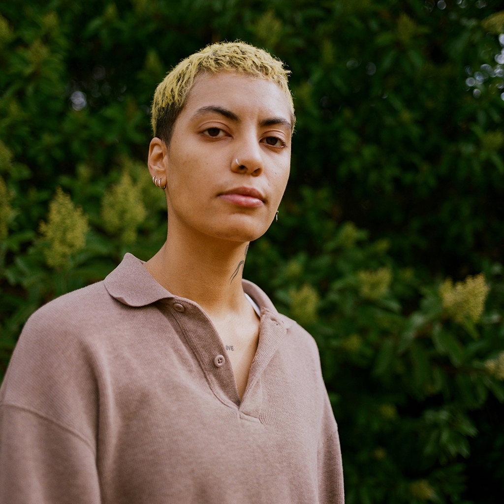 Christina Moreland standing in front of a line of trees and looking into the camera.