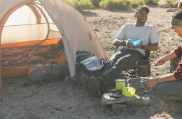 Two campers enjoy a meal together over a backpacking stove