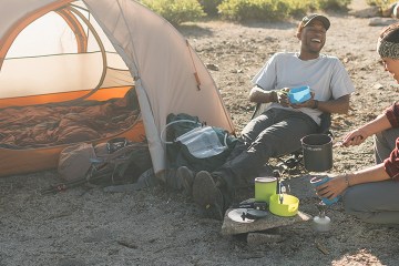 Two campers enjoy a meal together over a backpacking stove
