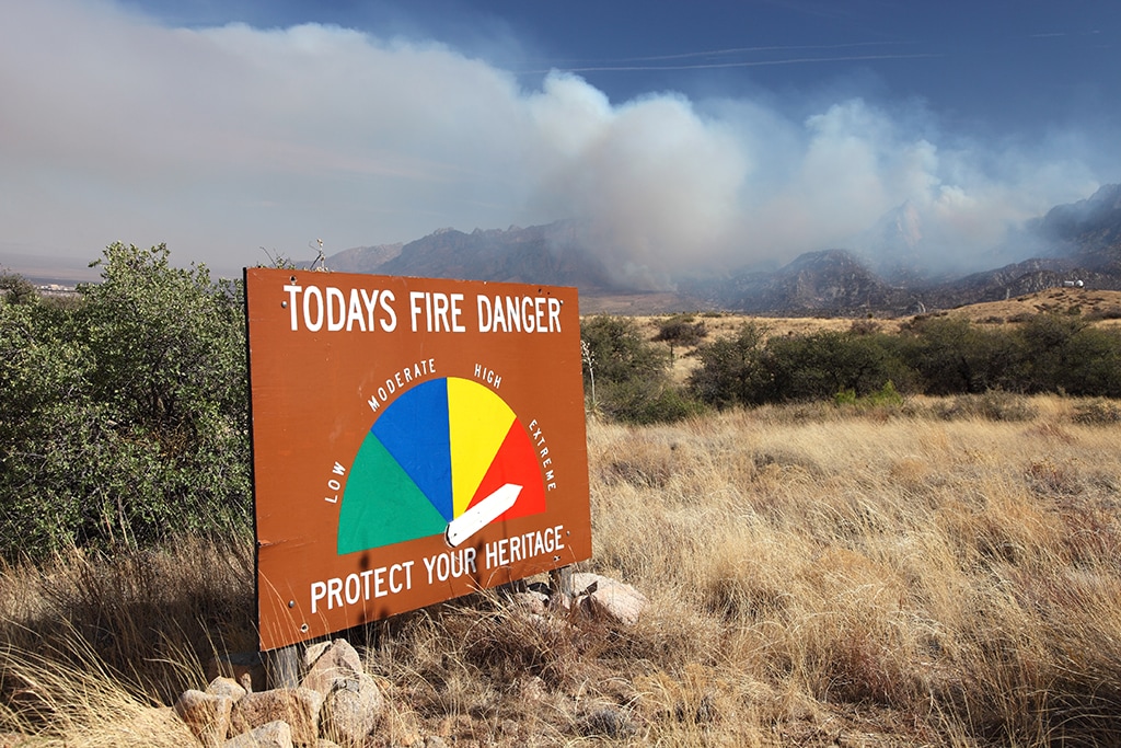 Fire danger warning sign in front of smoke-obscured scenery