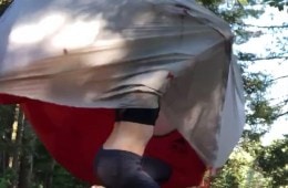 Person inside a tent trying to hold it down as wind blows it away.