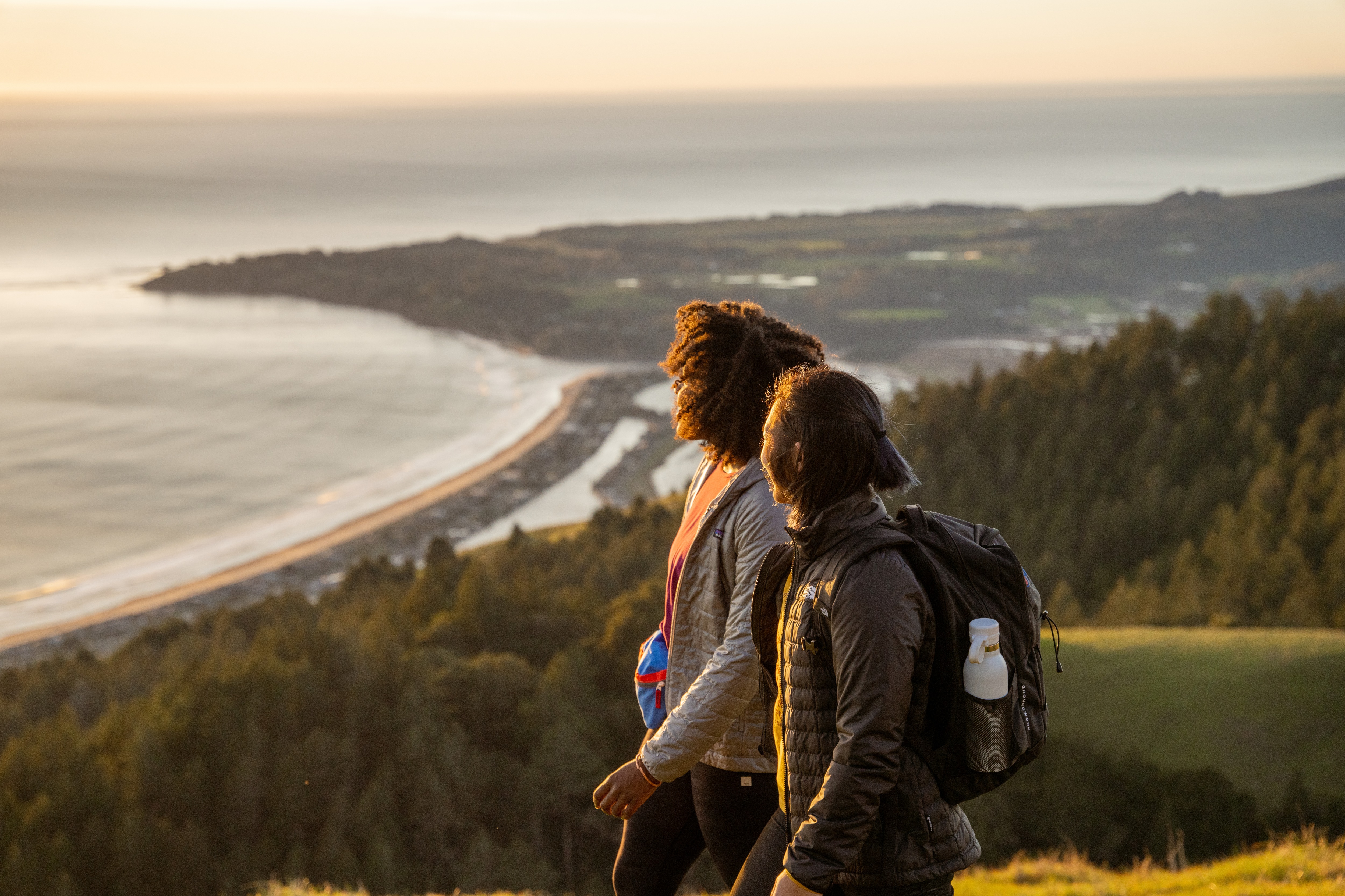 Two hikers looking out at a large body of water.