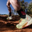 Person running in a pair neon-yellow-and-orange of adidas Agravic Flow 2 trail running shoes on a dirt trail.