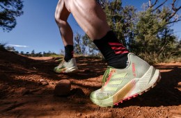 Person running in a pair neon-yellow-and-orange of adidas Agravic Flow 2 trail running shoes on a dirt trail.
