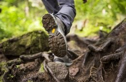A person walking through a muddy forest in hiking boots