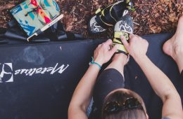 Climber sitting on a crash pad putting climbing shoes on.