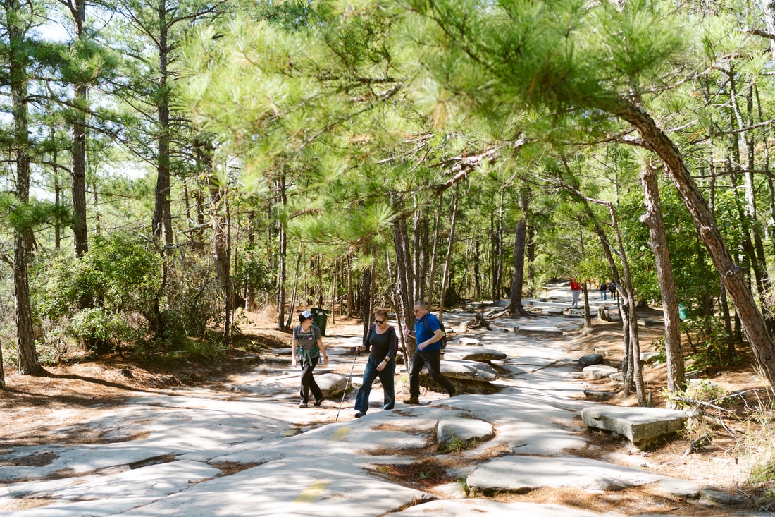 Three people hike on a rocky trail.