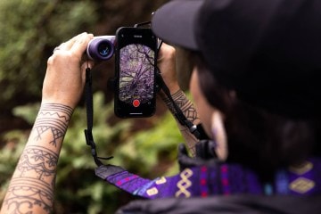 Artist Amelia Winger-Bearskin takes a photo through a pair of Nocs Binoculars