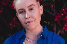 Portrait of Fiona Lowenstein, wearing a royal blue shirt over a white tank top.