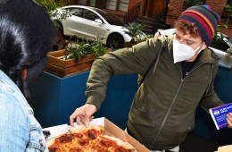 A voter grabs a slice of pizza while waiting in line