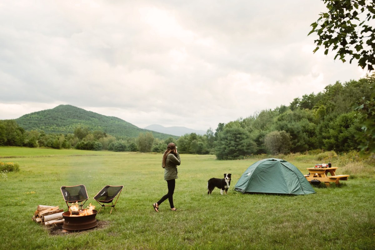 Picture of a young woman and her dog at a campsite with a lot of greenery.