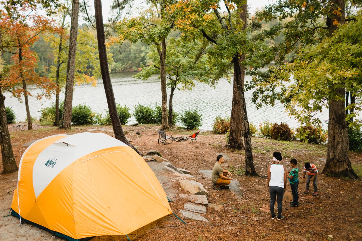 A bright photo of a family camping near a body of water.