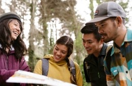 Four people looking at a map in a wooded area