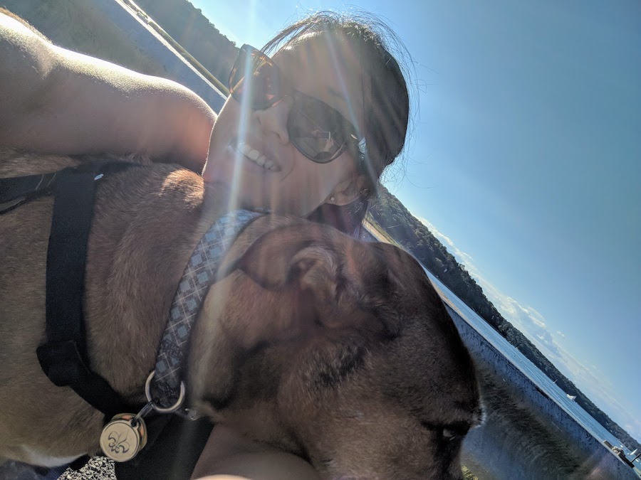 A selfie of a woman with her brown dog on a sunny day.