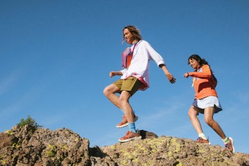 Two smiling hikers on rocky terrain.