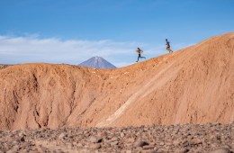 Two runners traversing a mountain ridge, wearing clothing from the Janji Runterra Bio collection