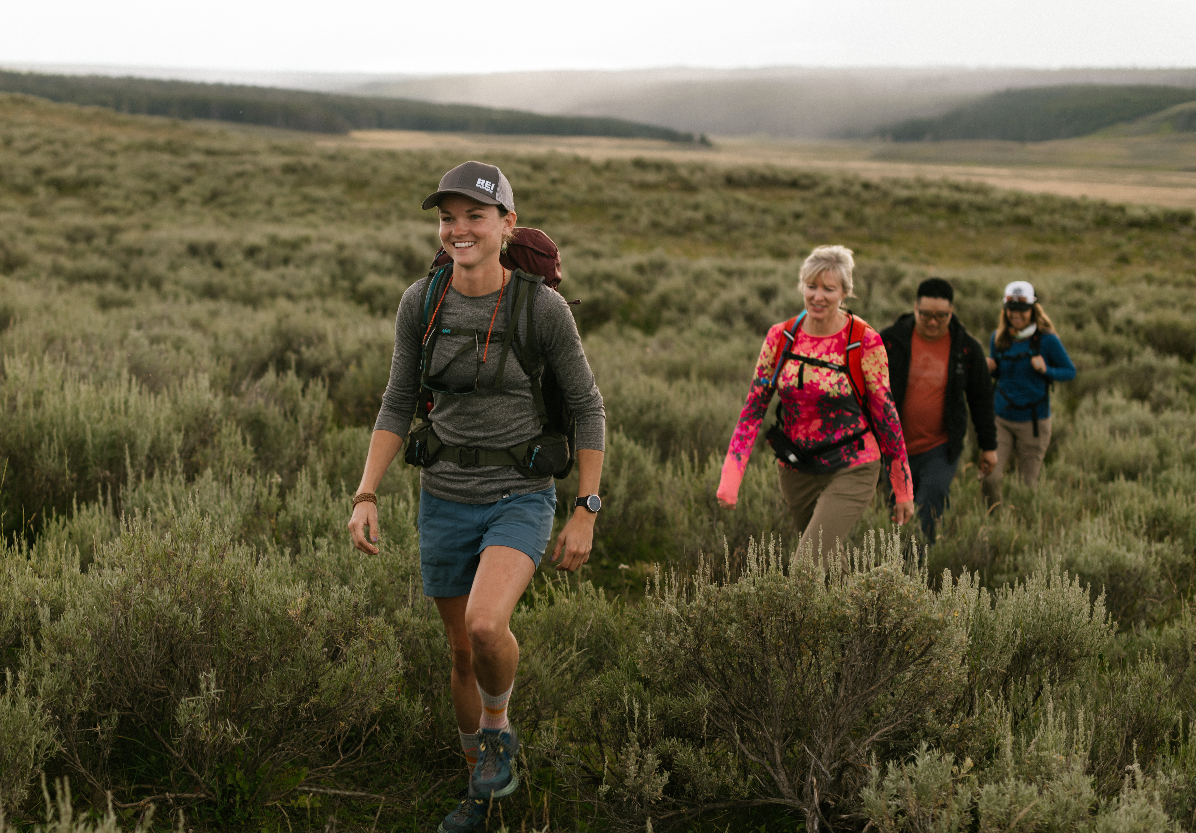 A group of 4 people hiking through a field on a guide REI trip of Yellowstone & Grand Tetons