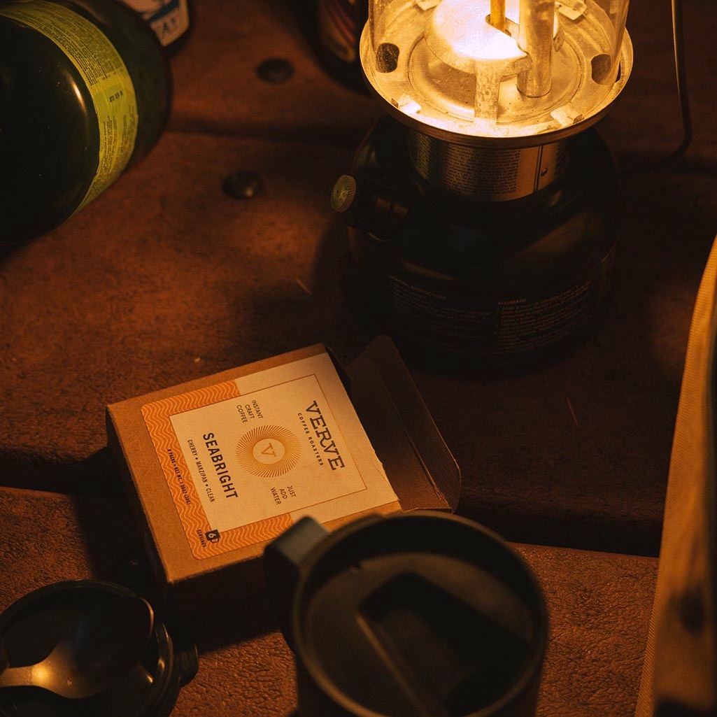 A box of instant coffee is lit up by a camp lantern