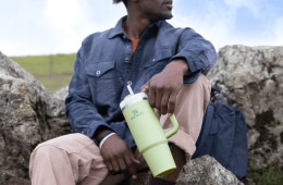 A man holds a light green Stanley Quencher.