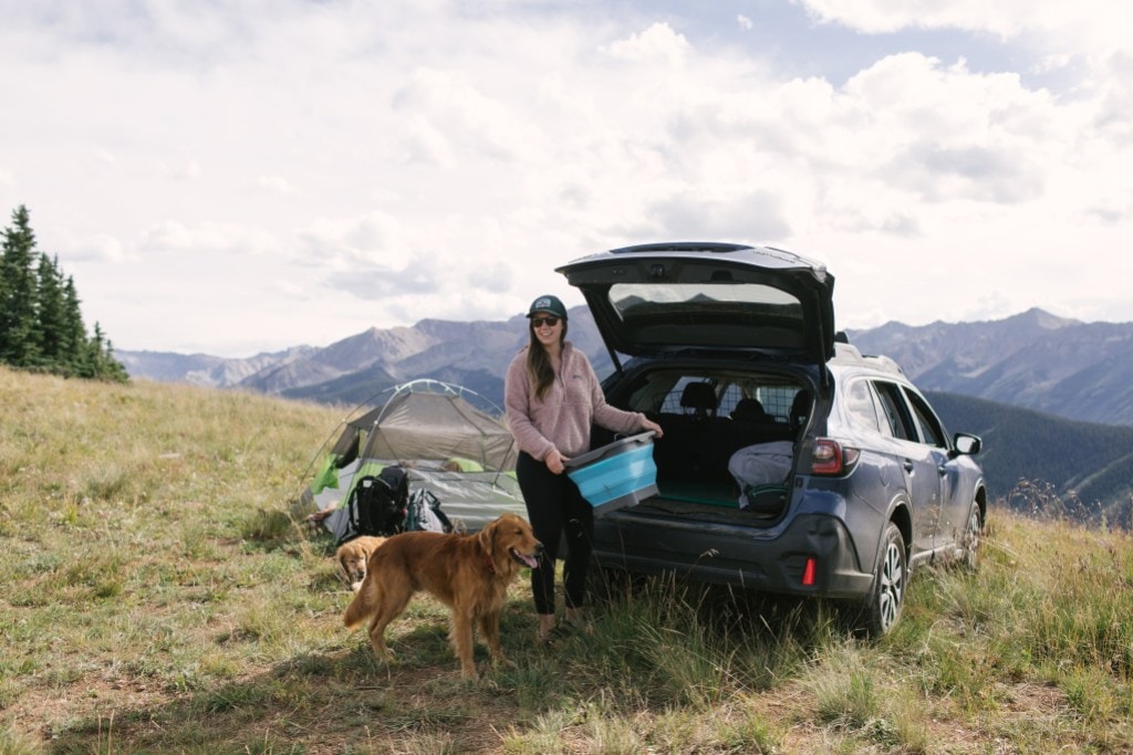 A woman unloads her car at her campsite.