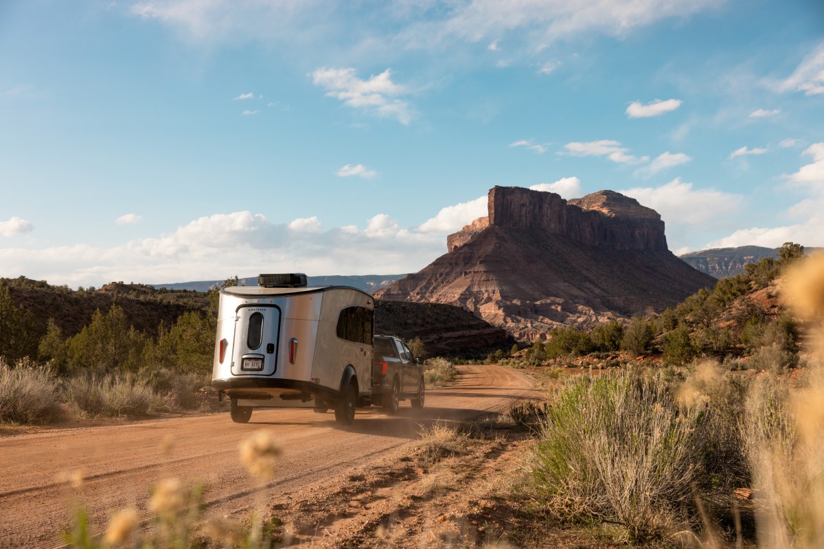 Photo of an Airstream trailer pulled behind a truck through the desert.