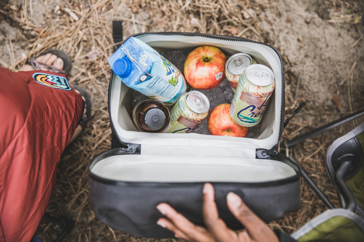 Picture of a small cooler filled with ice, apples and drinks.