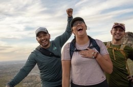Three people laughing outside on a hike
